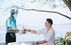 a man in a mask shaking another mans hand at Dinuda Resort in Kalpitiya