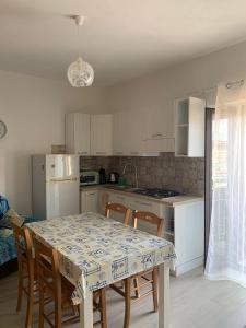 a kitchen with a table and chairs and a kitchen with white cabinets at Casa di nonna Marianna in Baunei