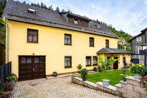 a yellow house with a garage and a yard at Ferienwohnung Josi Unterweißbach in Unterweißbach