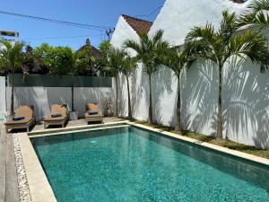 a swimming pool next to a fence with palm trees at Villa Oberoi 2 bedrooms in Seminyak
