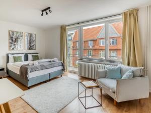 1 dormitorio con cama, sofá y ventana en limehome Kassel Motzstraße en Kassel