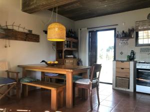 a kitchen with a wooden table with chairs and a light at Casa Bacana in Punta Del Diablo