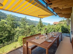 a wooden table on a patio with a view of mountains at Holiday Home Pfisterer - BRG150 by Interhome in Taxenbach