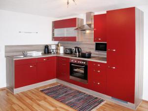 a kitchen with red cabinets and a stove at Holiday Home Moosen - NKI210 by Interhome in Neukirchen am Großvenediger