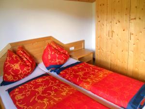 a bedroom with two beds with red and orange pillows at Holiday Home Auer - EBE116 by Interhome in Eben im Pongau