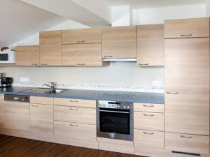 una cocina con armarios de madera y fregadero en Apartment Tauernblick - BMG190 by Interhome, en Bramberg am Wildkogel