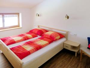 1 dormitorio con 2 camas con almohadas rojas y amarillas en Apartment Tauernblick - BMG190 by Interhome, en Bramberg am Wildkogel
