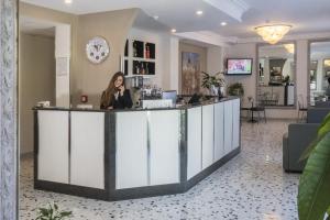 a woman standing at a reception desk in a lobby at Hotel La Pergola in Sant'Agnello