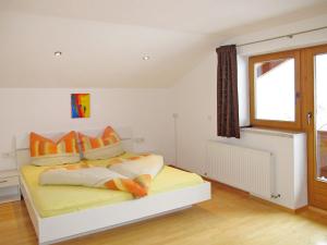 - une chambre avec un lit doté d'oreillers orange et une fenêtre dans l'établissement Apartment Unterkreuter - KAB215 by Interhome, à Kaltenbach