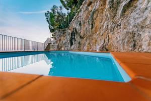 a swimming pool next to a rock wall at Villa Eris Amalfi Coast in Conca dei Marini