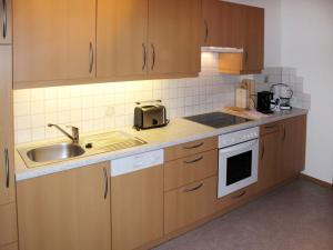 - une cuisine avec des placards en bois et un évier dans l'établissement Apartment Taxacher - ZAZ765 by Interhome, à Aschau
