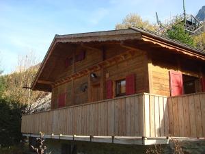 eine große Holzhütte mit roten Türen auf einem Berg in der Unterkunft Chalet Evasion by Interhome in Les Bossons