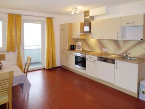 a kitchen with white cabinets and a wooden floor at Apartment Haus Huber - ZAZ403 by Interhome in Zell am Ziller