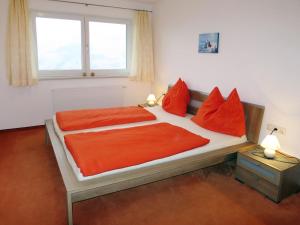 a bedroom with a bed with red pillows and a window at Apartment Haus Huber - ZAZ403 by Interhome in Zell am Ziller