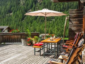 einen Tisch und Stühle mit einem Sonnenschirm auf einer Terrasse in der Unterkunft Apartment Beim Holzschnitzer-2 by Interhome in Sölden