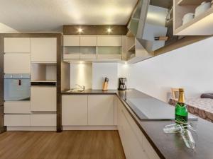a kitchen with white cabinets and a bottle of wine on the counter at Apartment Chalet Modern Life - MHO769 by Interhome in Ramsau im Zillertal
