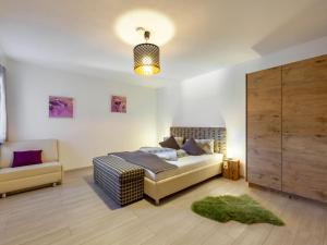 a bedroom with a bed and a couch and a chair at Apartment Chalet Modern Life - MHO769 by Interhome in Ramsau im Zillertal