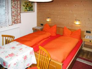 sypialnia z 2 łóżkami z pomarańczowymi poduszkami i stołem w obiekcie Apartment Barbara - ZAZ614 by Interhome w mieście Aschau