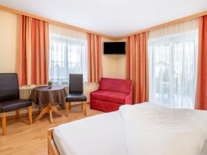 a bedroom with a bed and a red chair and a table at Apartment Rosa-3 by Interhome in Mayrhofen +34 photos