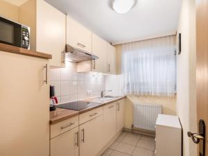 una pequeña cocina con armarios blancos y fregadero en Apartment Rosa - MHO135 by Interhome en Mayrhofen
