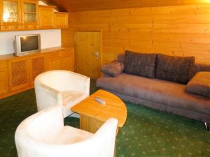 een woonkamer met een bank, stoelen en een tv bij Apartment Gratzerhof-1 by Interhome in Finkenberg