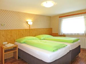 a bedroom with two beds with green pillows and a window at Apartment Oberkofl - LNH300 by Interhome in Tux