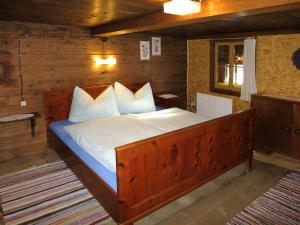 - une chambre avec un grand lit en bois et des oreillers blancs dans l'établissement Chalet Lippnerhütte - LNH120 by Interhome, à Tux