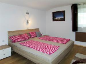 Una cama con almohadas rojas y blancas. en Apartment Margret by Interhome, en Längenfeld