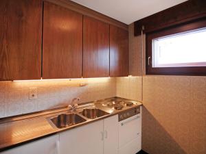 eine Küche mit Holzschränken, einem Waschbecken und einem Fenster in der Unterkunft Apartment Pigne 1 by Interhome in Verbier