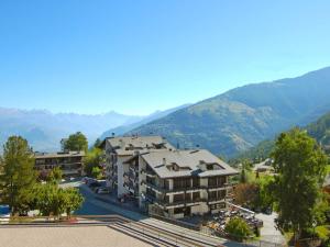 ein Apartmenthaus mit Bergen im Hintergrund in der Unterkunft Apartment Valaisia 34A by Interhome in Nendaz