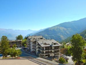an apartment building with mountains in the background at Apartment Valaisia 34A by Interhome in Nendaz