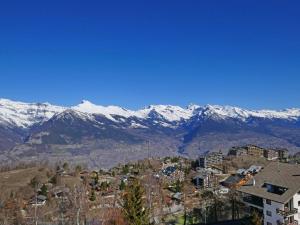 una ciudad con montañas cubiertas de nieve en el fondo en Apartment Eden Roc 28 by Interhome, en Nendaz