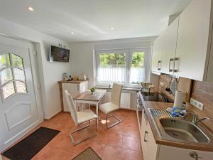 a kitchen with a sink and a table with chairs at FeWo "Hoffi" am Waldesrand in Baabe