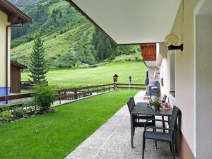 un patio con tavolo, sedie e campo verde di Apartment Daheim – Edelweiß - PZT382 by Interhome a Plangeross