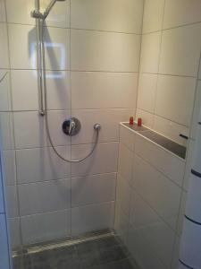 a shower with a hose in a white tiled bathroom at FeWo "Hoffi" am Waldesrand in Baabe