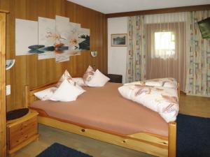 una camera da letto con un grande letto con cuscini bianchi di Apartment Daheim – Edelweiß - PZT382 by Interhome a Plangeross