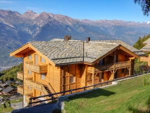 a log house on a hill with mountains in the background at Apartment La Corniche 2 by Interhome in Nendaz