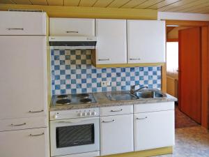 eine Küche mit weißen Schränken, einer Spüle und einem Herd in der Unterkunft Apartment Elfriede - SZU123 by Interhome in See