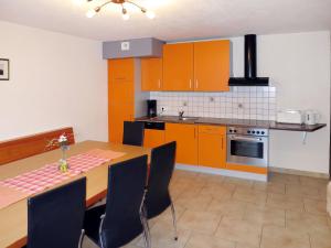 a kitchen with orange cabinets and a table with chairs at Apartment Apart Sonja - KPL648 by Interhome in Kappl