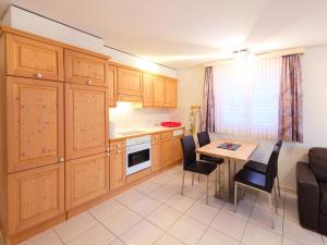 eine Küche mit Holzschränken und einem Tisch mit Stühlen in der Unterkunft Apartment Roger-2 by Interhome in Zermatt