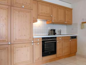 una cocina con armarios de madera y horno negro en Apartment Roger-2 by Interhome en Zermatt