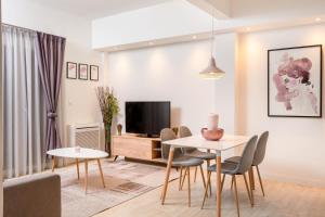 uma sala de estar com uma mesa e cadeiras e uma televisão em Athens Morum City Apartments em Atenas