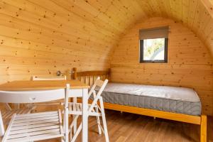 Camping Pods Trevella Holiday Park في كرنتك: غرفة بسرير وطاولة في كابينة