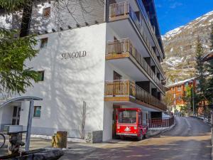 um edifício com um camião vermelho estacionado em frente dele em Apartment Sungold-1 by Interhome em Zermatt