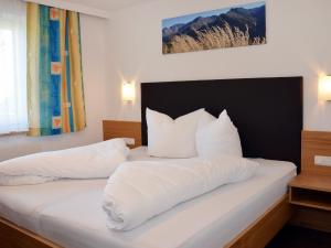sypialnia z łóżkiem z białą pościelą i poduszkami w obiekcie Apartment Schranz - KPL520 by Interhome w mieście Kappl