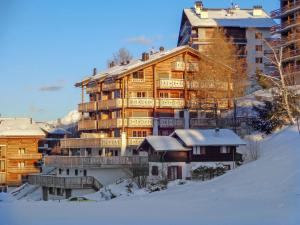 a large wooden building in the snow in front at Apartment Les Terrasses du Paradis 5a by Interhome in Nendaz