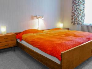a bedroom with a large bed with an orange blanket at Apartment Dianthus-1 by Interhome in Zermatt