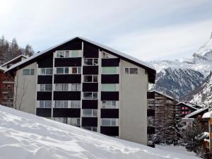 um edifício na neve com montanhas ao fundo em Apartment Roc by Interhome em Zermatt