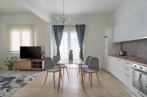 una cucina con tavolo, sedie e TV di Athens Morum City Apartments ad Atene