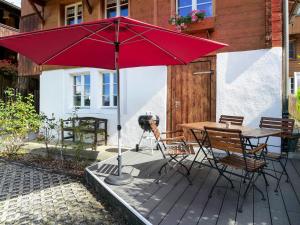 einen roten Regenschirm auf einer Holzterrasse mit einem Tisch und Stühlen in der Unterkunft Chalet Hüsli by Interhome in Brienzwiler